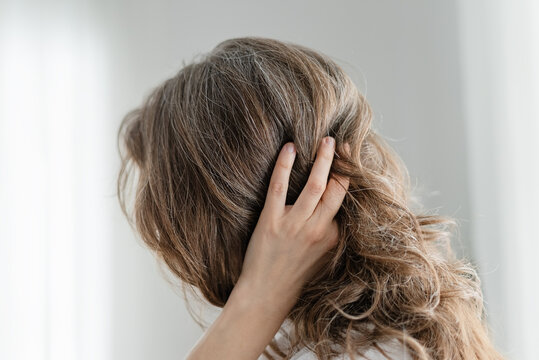 A woman celebrates her natural hair color which includes beautiful gray strands throughout. The mature adult refuses to dye and embraces authenticity completely. Mother loves genuine silver locks