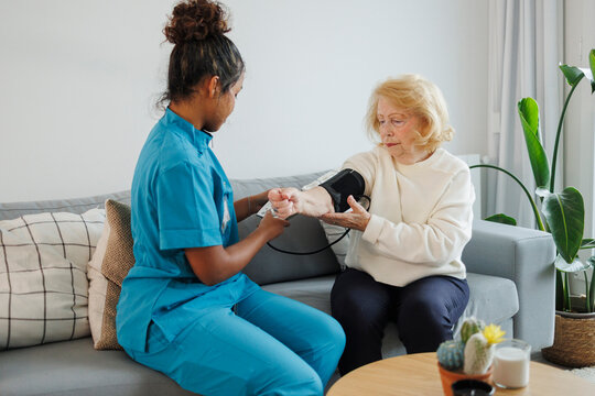 Nurse checking blood pressure of elderly woman during home healthcare