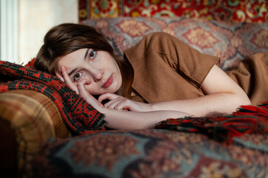 Young woman lying on sofa with vintage bedding in old house