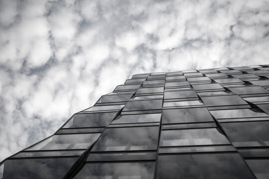 Urban monochrome architecture of a modern building facade where windows meet clouds in a repeating pattern with deep perspective detail