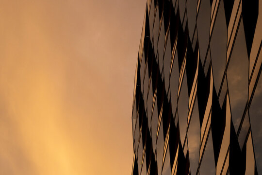 Minimal modern architecture of a glass facade building silhouette at sunset with soft gradient sky creating a calm contemporary backdrop