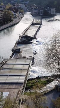 Vertical footage of water flowing through a small river dam in a European city to generate hydroelectric power and mitigate flooding
