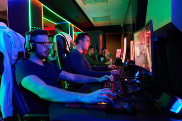 Competitive Gamers Playing Multiplayer PC Games In Neon-Lit Esports Gaming Arena With Headsets