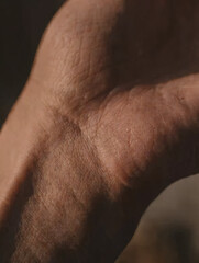 Fototapeta premium Extreme macro close-up of an elderly person's hand showing detailed skin texture, wrinkles, and pores, conceptual image of aging and human life story