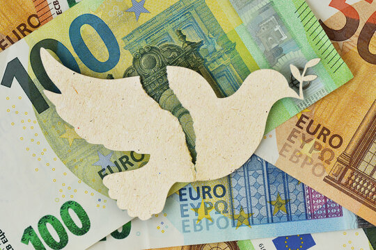 Torn paper dove on euro bankonotes background - Concept of war and economic impact