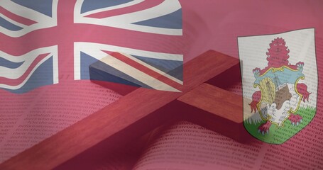 Obraz premium Displaying wooden cross resting across open book on table, with Bermuda flag showing Union Jack