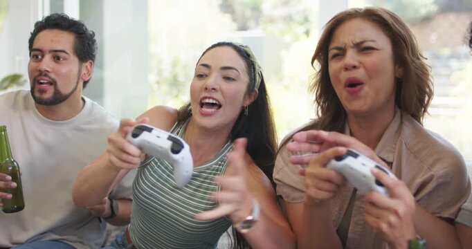 Diverse friends pressing button, playing game on couch at home with controllers, bottles for fun