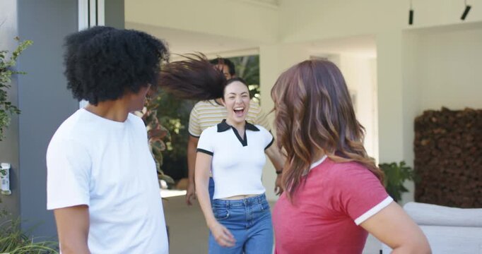Friends reuniting in T-shirts and polo, folding door opening, two running and embracing threshold