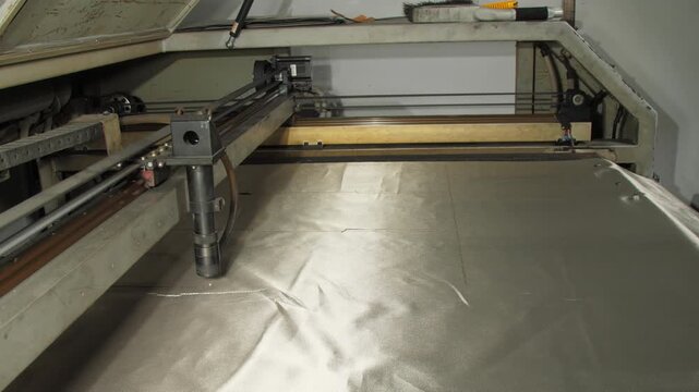 Cutter precisely maneuvers over shielding fabric closeup. Machine slices through blocking material to create sheets for specialized applications