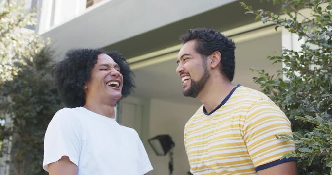 African American male friends laughing during chat, pointing at camera, showing watches at entrance