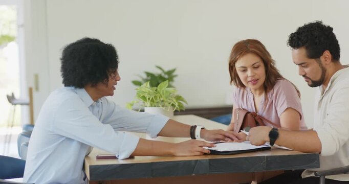 African American couple meeting agent left sliding sheet reading documents checking key for closing