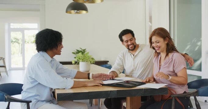 African American couple and agent shaking hands, finalizing purchase at dining table, handing keys