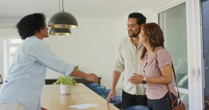 Couple with agent handing keys, shaking hands, celebrating purchase at kitchen table