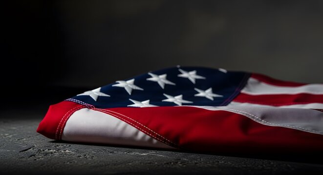Folded American flag resting on a dark surface, symbolizing respect and remembrance.
