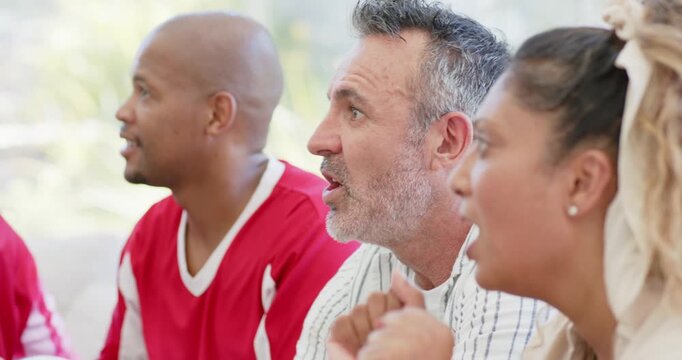 Diverse friends on couch in red jerseys and striped shirt leaning forward, gasping at off-frame TV
