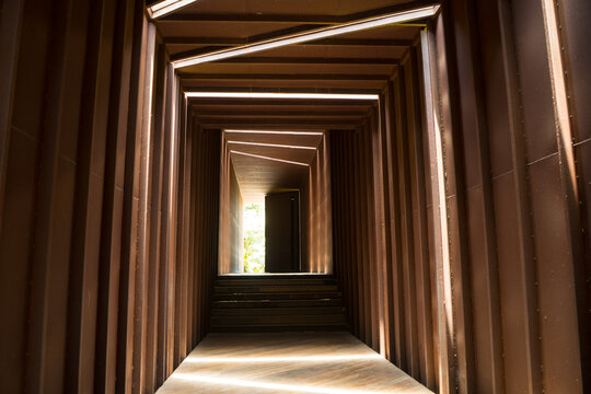Steel of rusty iron patterns with beams of sunlight and shadows within the tunnel throughout the day. At the end of the tunnel. Vintage modern design of building.