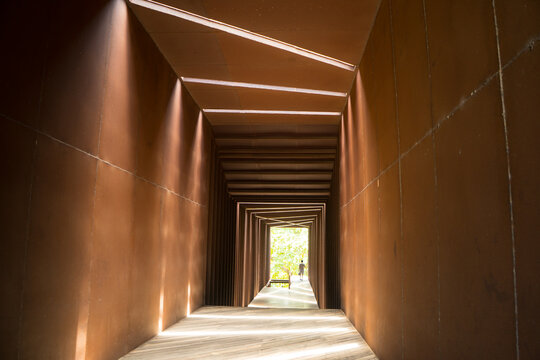 Steel of rusty iron patterns with beams of sunlight and shadows within the tunnel throughout the day. At the end of the tunnel. Vintage modern design of building.