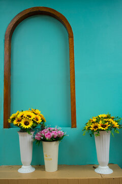 Colorful flower blooming in the jar in front of the green vintage wall background