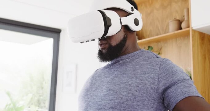 African man putting on white VR headset, reaching and selecting virtual objects at home