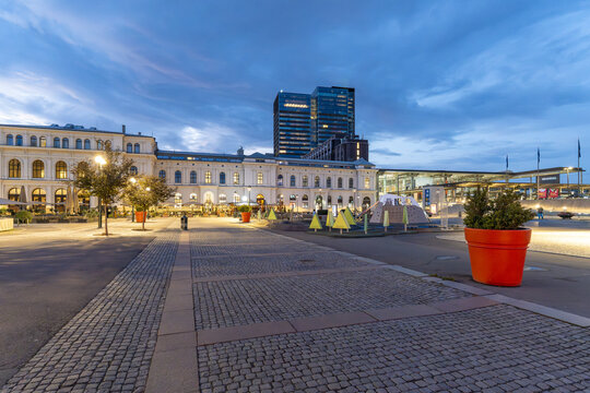 View of cobbles lead the eye towards the glowing Oslo Central Station and the Barcode buildings under a dusk sky, Oslo, Norway.