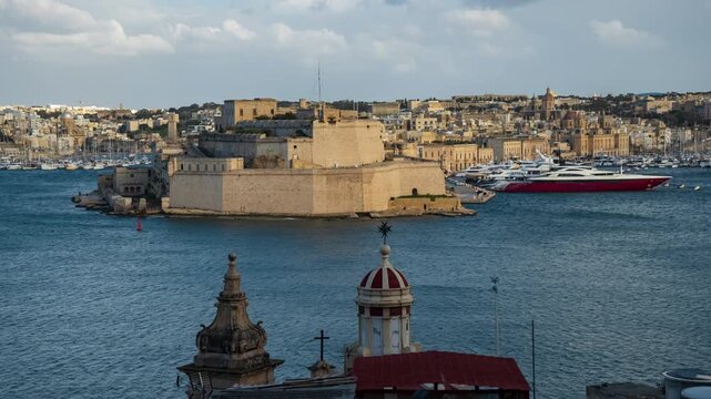 Timelapse Fort St Elmo coastal walls in Valletta under sunny weather, massive limestone fortifications above sea and moored luxury yachts in harbor. Shifting light and shadows animate historic scene