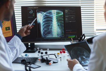 Doctors reviewing chest x ray scan on monitor, discussing AI assisted diagnosis in medical office....