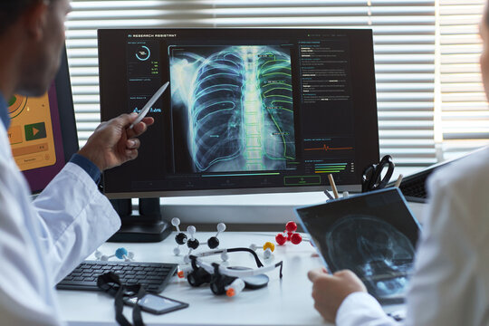 Doctors reviewing chest x ray scan on monitor, discussing AI assisted diagnosis in medical office. Ideal for healthcare technology, radiology, diagnostics, innovation marketing