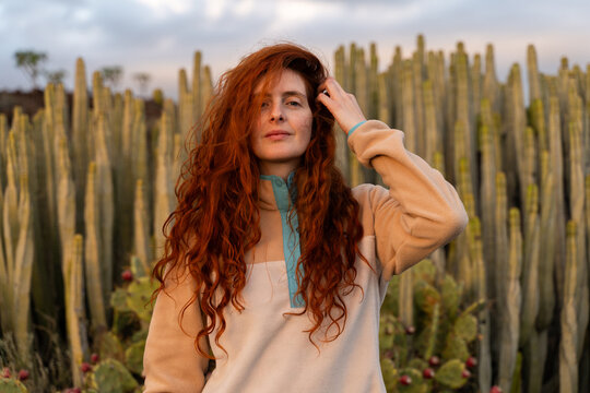 Portrait of red haired woman at sunset in desert with cactus