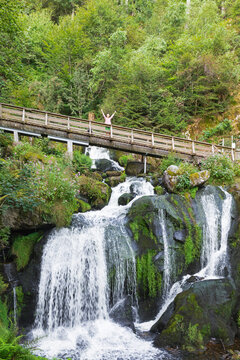 Woman cheering on bridge over Triberg Waterfall in Black Forest