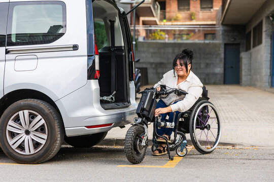 Woman connecting wheelchair handbike to accessible van outdoors