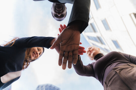 Business colleagues joining hands in unity and teamwork outdoors