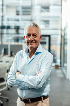 Smiling boss in modern office with arms crossed