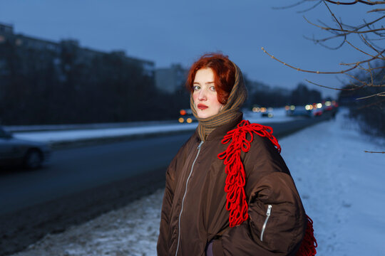 Red haired woman with red bag outdoors in winter evening