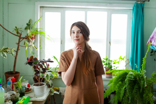 Woman in brown dress standing indoors in old house with plants