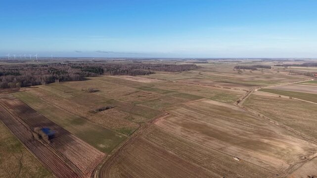 Aerial footage captures expansive rural farmland stretching across the horizon. Clear skies and a bird's eye view showcase the vast, serene fields under bright sunlight, perfect for agriculture.