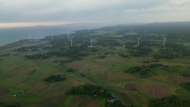 Aerial drone shot of wind turbine farm amid lush agricultural fields at quaint tropical island village - Guimaras, Visayas, Philippines