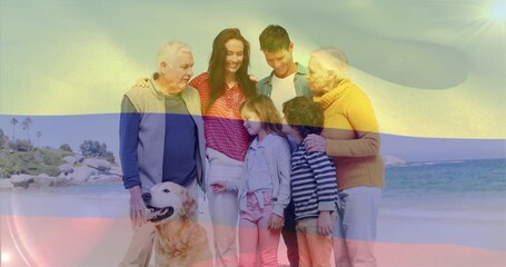 Fototapeta premium Standing three-gen family posing on beach in casual clothes, golden retriever panting, color bands