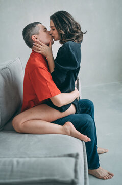 Couple embracing and kissing on a sofa in a cozy indoor setting