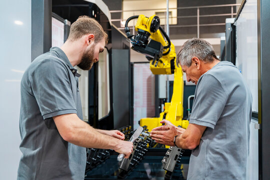 Engineers discussing in a production hall with an industrial robot