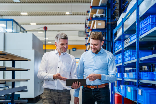 Colleagues discussing business using tablet in factory production hall