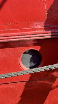 low Motion Sun Reflection on Red Boat Porthole and Metal Surface