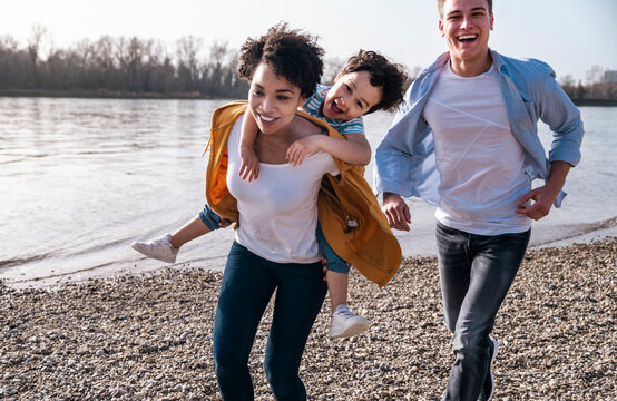 Family having fun running by the river on a pebble beach outdoors