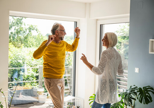 Happy couple dancing and smiling together at home in living room