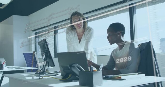 Two colleagues at desk operating laptop, pointing and analyzing biz timeline overlay for planning
