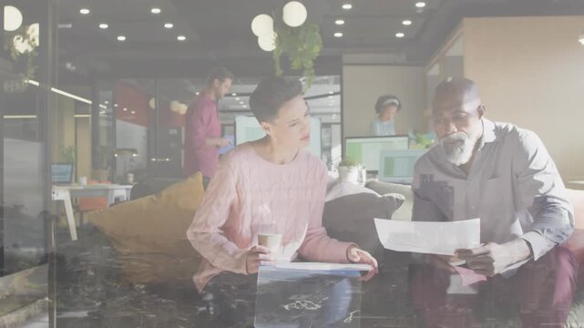 Animation of diverse coworkers discussing reports holding coffee cups over aerial view of city