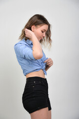 Fototapeta premium Junge Frau im bauchfreien Denim-Outfit, skinny Figur und lässiger Look, nachdenkliche Pose, modernes Fashion- und Lifestyle-Porträt