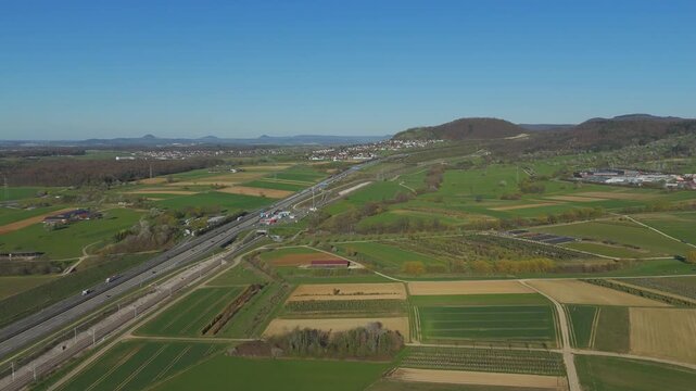 Aerial view of highway traffic on A8 near Aichelberg in spring, clear blue sky and wide landscape with view toward the Three Kaiser mountains, Baden Wurttemberg, Germany.
