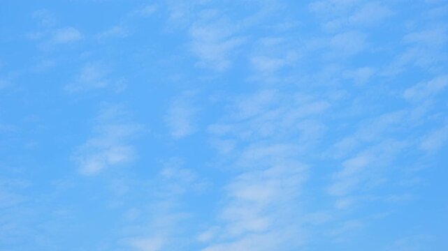 A blue sky timelapse video footage featuring soft altocumulus cloud patterns drifting across a clear sky, creating a calm, airy atmosphere with gentle motion and natural daylight tones. 4k.

