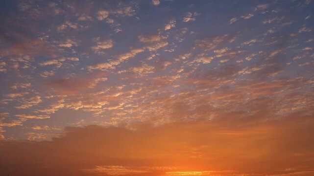 A sunrise sky timelapse video footage with scattered altocumulus clouds across a blue sky, illuminated by soft golden light at the horizon, creating a calm and expansive morning atmosphere. 4k.
