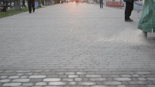 Man in airtight suit sprays disinfecting liquid chemicals antiseptic on street in city on day. Sanitation workers clean pavement, crosswalk. Sanitary measures in public place. Coronavirus pandemic